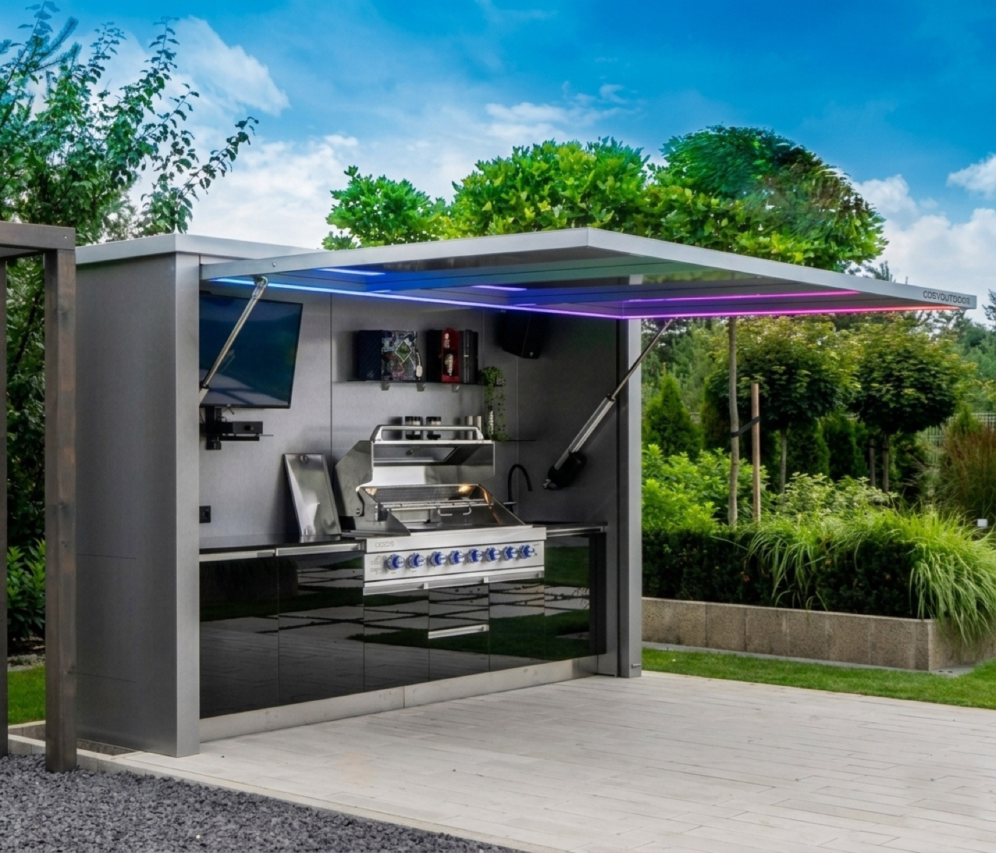 Cuisine d'été extérieure : bloc inox avec plancha et capot relevable, dans le jardin — photo réelle